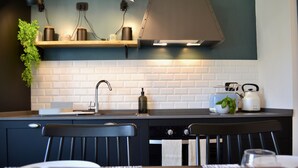 A modern kitchen with a white tiled backsplash, a wooden countertop, and a black chair. - Cosy Home Riviera 3BDR (Chiavari)