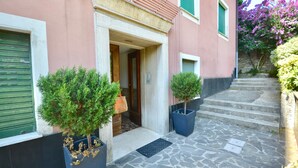 A building with a stone-paved entrance, a door, and two potted plants. - Cosy Home Riviera 3BDR (Chiavari)