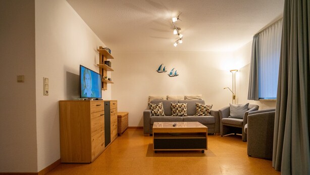 A living room with a sofa, a coffee table, a TV, and a lamp. - Wohnung Felber am Ostdeich (Büsum)