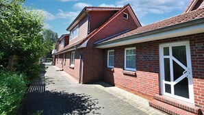Een tweelaags bakstenen huis met schuin dak, een veranda en een klein raam.