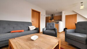 Ett modernt vardagsrum med en grå soffa, en grå fåtölj och ett soffbord i trä.