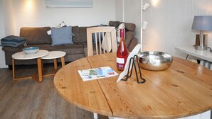 Ein gemütliches Wohnzimmer mit einem braunen Sofa, einem Holztisch und einer weißen Lampe.