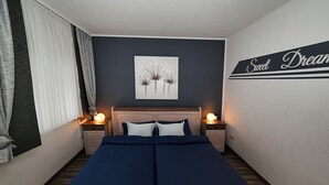 A bedroom with a bed, two bedside tables with lamps, a wall art piece, and a sign that says "Sweet Dream". - Haus Schäfer Wohnung 1 in Ruhiger Lage (Büsum)