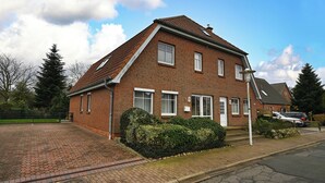 A two-story brick house with a sloped roof, multiple windows, and a small front garden. - Haus Schäfer Wohnung 1 in Ruhiger Lage (Büsum)
