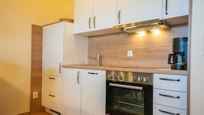Een moderne keuken met witte kastjes, een inbouwoven en een koffiezetapparaat.