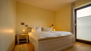 Een slaapkamer met een bed, nachtkastjes en een raam met zonwering.