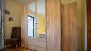 Een slaapkamer met een houten garderobe, een stoel en een bed.