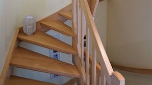 Een houten trap met een witte vaas op de overloop.