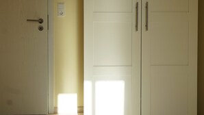 Een kamer met een houten vloer, een witte deur en een witte garderobe met twee deuren.