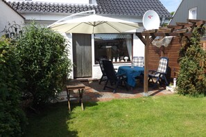 A patio with a table and chairs, a pergola, and a satellite dish. - Haus "reinhard" in Ruhiger Lage Direkt am Wäldchen (Büsum)