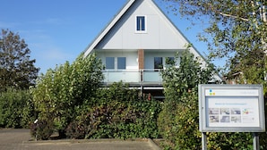 Ein modernes, zweistöckiges Haus mit einem Mansarddach, einem kleinen Fenster und einem Balkon.