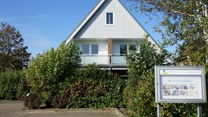 Et moderne hus med to etager, et trekantet tag, et lille vindue og en balkon.