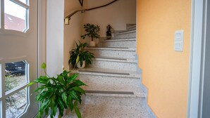 A staircase with a handrail, potted plants, and a wall-mounted light fixture.