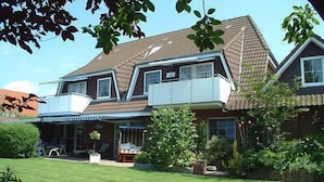 A two-story house with a sloped roof, a covered porch, and a well-maintained lawn.