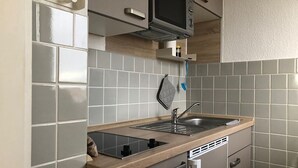 Een compacte keuken met een inbouwmagnetron, een spoelbak en een kookplaat.