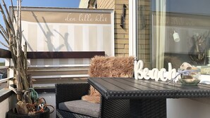 Een terras met rieten meubilair, een bord waarop 