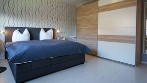 A modern bedroom with a large bed, a nightstand, and a wardrobe. - Wohnung Eil 809 im Herzen von Büsum (Büsum)