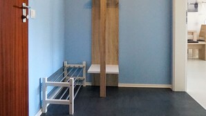 A room with a blue wall, a wooden shelf unit, and a white metal rack. - Wohnung Eil 809 im Herzen von Büsum (Büsum)