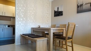 A dining area with a wooden table and chairs, a bench, and a wall with a floral pattern. - Wohnung Eil 809 im Herzen von Büsum (Büsum)