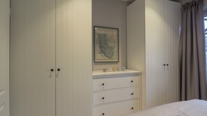 Um quarto com uma cama, uma cômoda com gavetas, um mapa na parede e uma janela com cortinas.