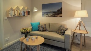 Uma sala de estar aconchegante com sofá, mesa de centro, abajur e estante de livros.