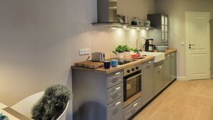 Eine moderne Küche mit grauen Schränken, einer Holz Arbeitsplatte, einem eingebauten Ofen und einer Kaffeemaschine.