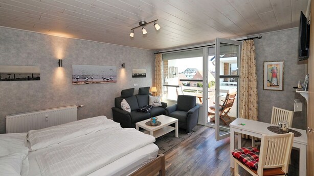 Een moderne hotelkamer met een bed, twee banken, een kleine tafel en een zithoek.