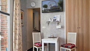 Een gezellige kamer met twee witte stoelen, een kleine tafel, een klok en een lijst met een foto van een reuzenrad.