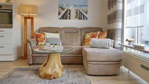A modern living room with a sectional sofa, a glass coffee table, and a wooden coffee table. - Seemeile 2.18 Seestern (Büsum)