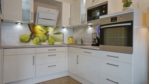A modern kitchen with white cabinets, a built-in microwave, and an oven. - Seemeile 2.18 Seestern (Büsum)