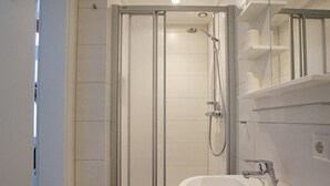 A modern bathroom with a glass-enclosed shower, a white sink, and a mirror. - Wohnung Deich Mitten in Büsum (Büsum)