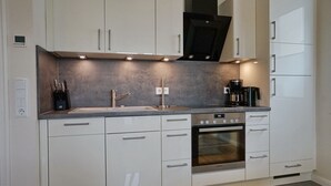 A modern kitchen with white cabinets, stainless steel appliances, and a grey countertop.