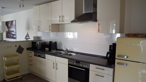 Una cocina moderna con armarios blancos, electrodomésticos de acero inoxidable y un carrito amarillo.