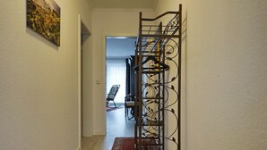 Un pasillo con un perchero metálico, un tapete rojo y un cuadro en la pared.