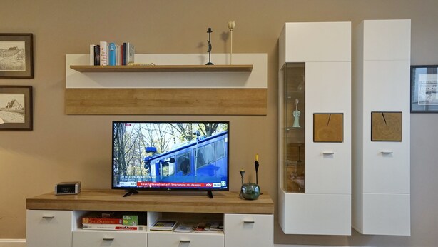 A modern living room with a flat-screen TV, wooden shelves, and built-in cabinets. - Wohnung Helios im Herzen von Büsum (Büsum)