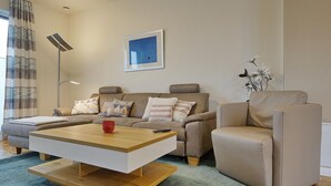 A modern living room with a sofa, armchair, and coffee table. - Wohnung Helios im Herzen von Büsum (Büsum)