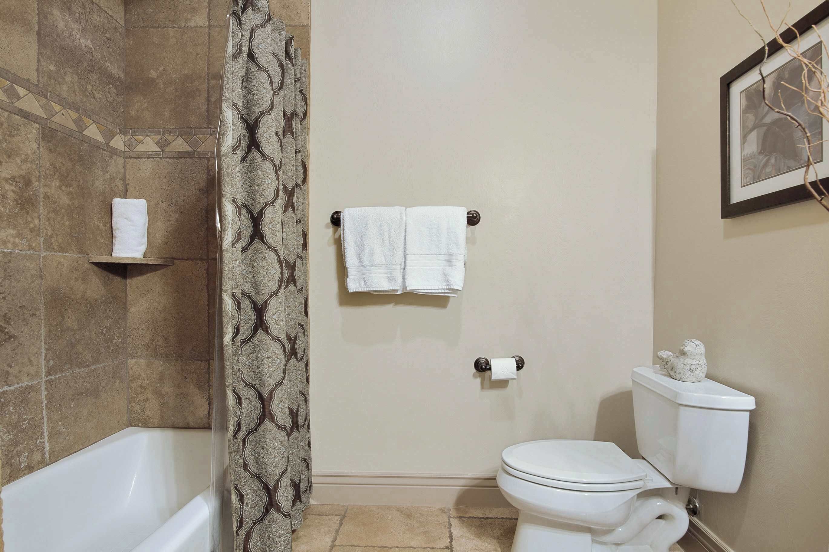 A bathroom with a bathtub, toilet, and shower curtain.