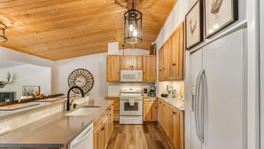 A modern kitchen with wooden cabinets, a central island, a microwave, stove, and a refrigerator.