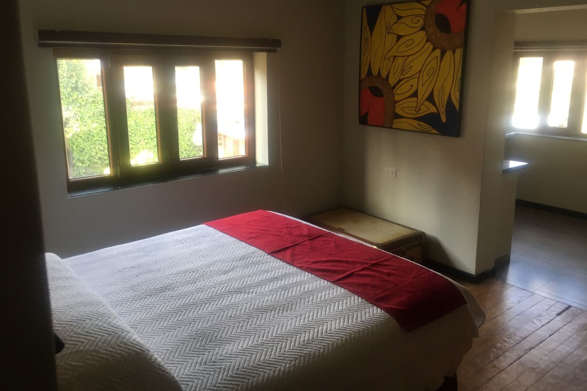 Un dormitorio con una cama, una ventana, un cuadro y un banco.
