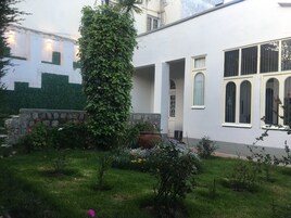 Un edificio blanco con pared de piedra y una columna grande cubierta de hiedra.
