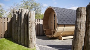 A wooden spa tub with a sloped roof, surrounded by wooden posts and a brick pathway. - Traumhafter Urlaub Unter Reet - Reethus "de Tweeling" Apartment OG (Büsum)