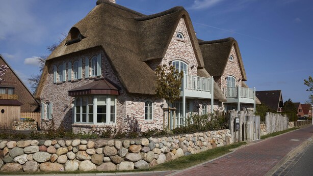 A stone house with a thatched roof and a stone wall in front. - Traumhafter Urlaub Unter Reet - Reethus "de Tweeling" Apartment OG (Büsum)