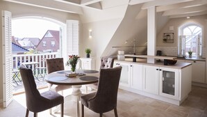 A modern kitchen with white cabinetry, a dining area with two chairs, and a view of the outside. - Traumhafter Urlaub Unter Reet - Reethus "de Tweeling" Apartment OG (Büsum)