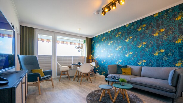Una sala moderna con un sofá, sillas, una mesa de centro y un televisor.