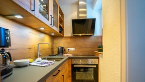 Una cocina moderna con armarios de madera, horno empotrado, microondas y cafetera.