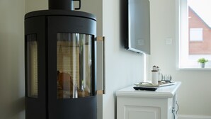 Une cuisine moderne avec un fourneau noir, des meubles blancs et une fenêtre donnant sur un immeuble.