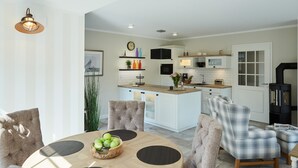 Une cuisine moderne avec des meubles blancs, un îlot central et un poêle à bois noir.