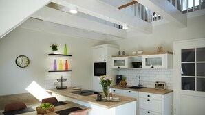A modern kitchen with white cabinetry, a wooden island, and a dining area with a wooden table and chairs. - Haus Daglind Apartment 3 mit Saunafass und Balkon (Büsum)