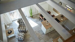 A modern interior with a sofa, coffee table, and a dining area with chairs and a wooden table. - Haus Daglind Apartment 3 mit Saunafass und Balkon (Büsum)