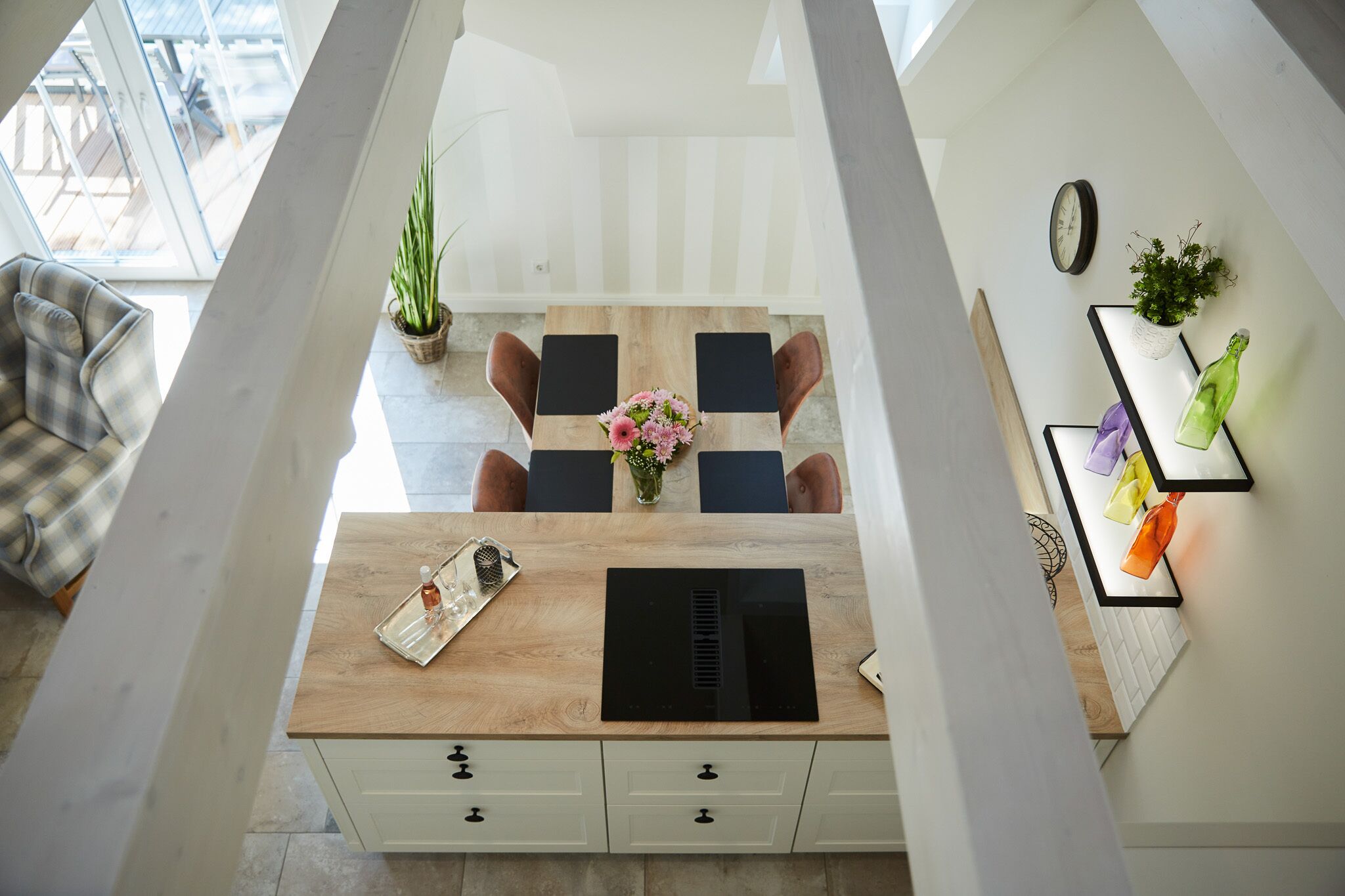 Une cuisine moderne avec un plan de travail en bois, des appareils électroménagers noirs et un coin repas comprenant une table et des chaises.